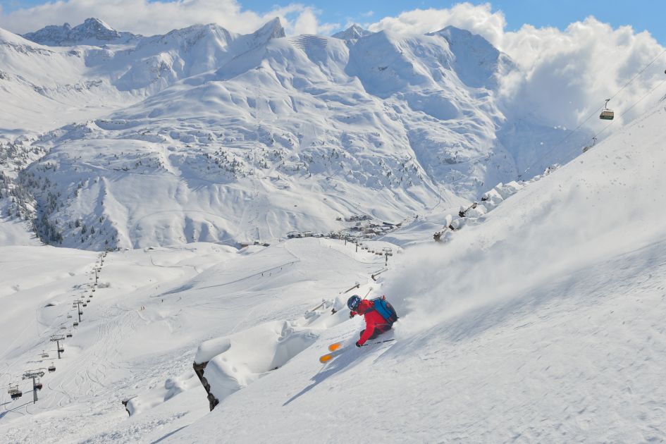 Off piste skiing in Lech, with the peak of the Valluga in the distance across the valley. 