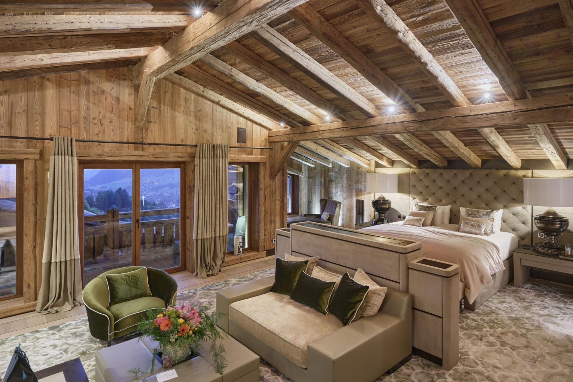 Luxurious ski chalet bedroom with wooden vaulted ceiling, picture windows with monutain views, and contemporary furnishings.