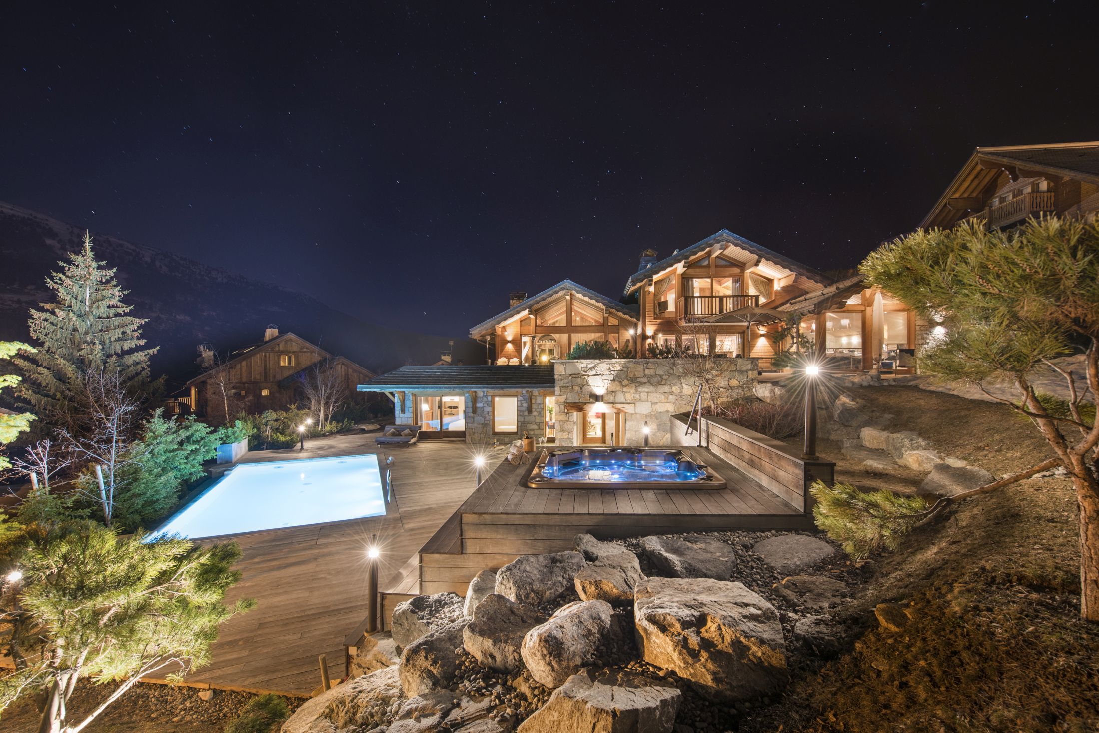 The exterior of Chalet Mont Tremblant, a luxury ski chalet in Meribel, featuring a luxury outdoor pool and hot tub with mountain views.