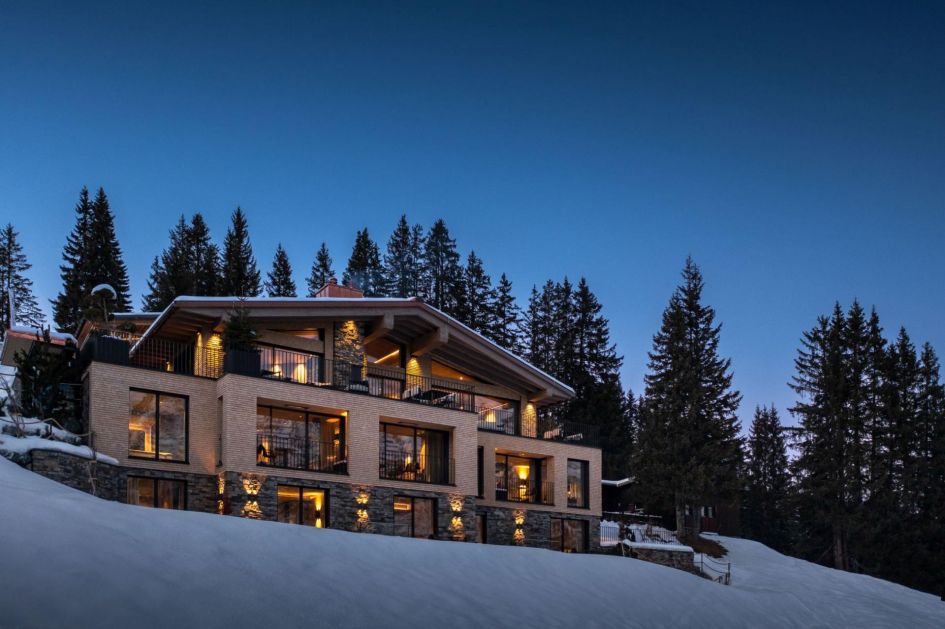 Exterior of Le Chalet in Lech, in front of fir trees.