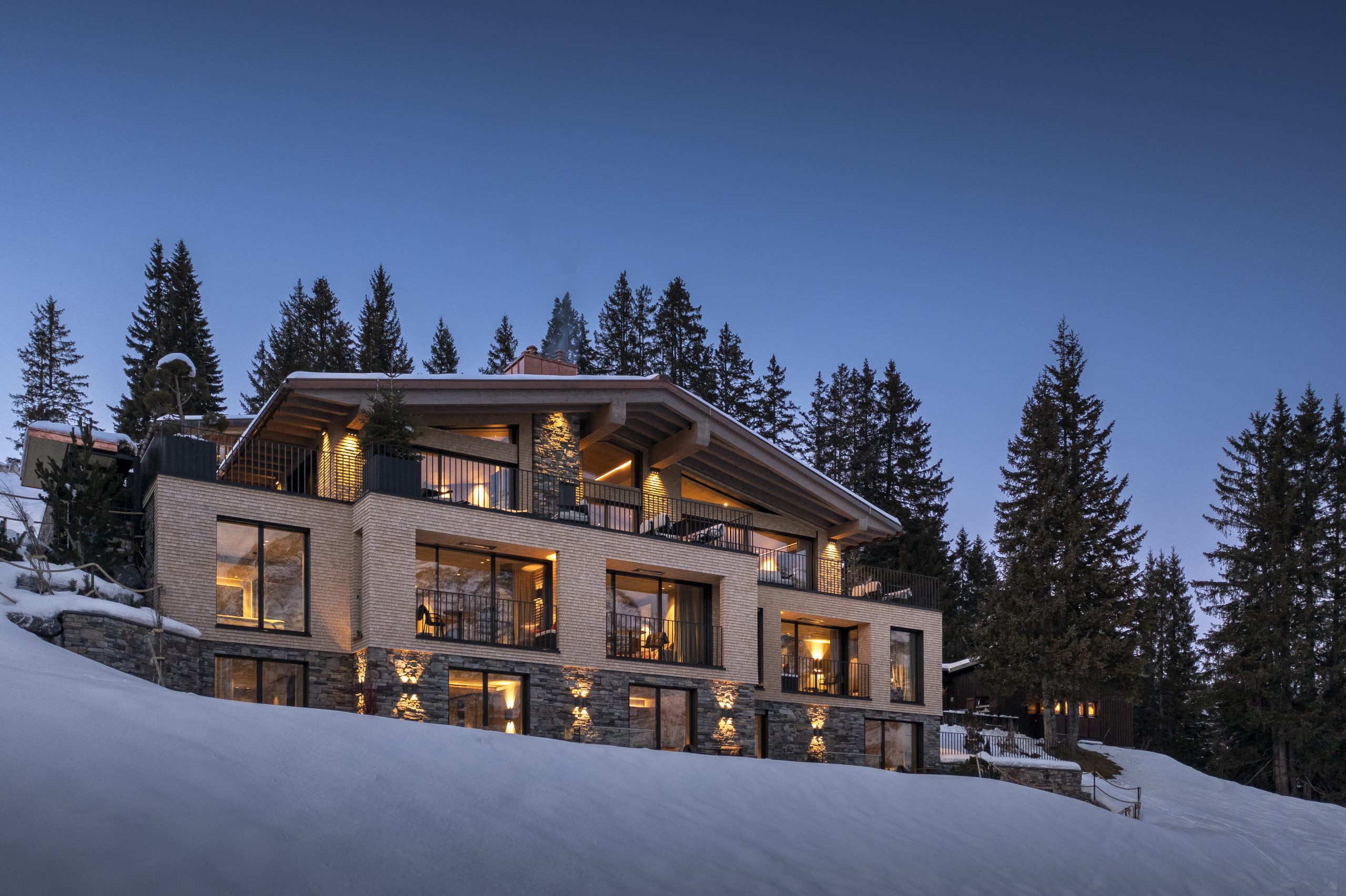 Exterior shot of Le Chalet, Lech. Taken at dusk with gorgeous lights coming from the inside of this luxury ski chalet in Austria.