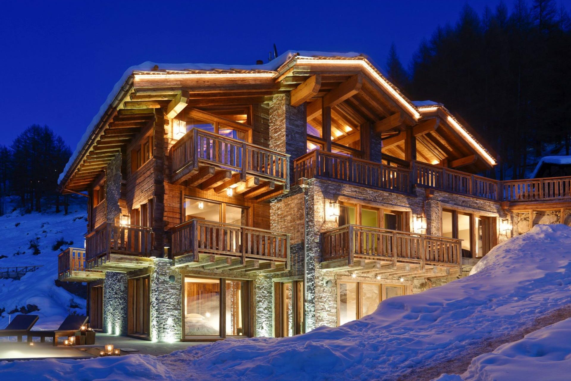 Exterior of Chalet Les Anges at night, lit up warmly and surrounded by snow.