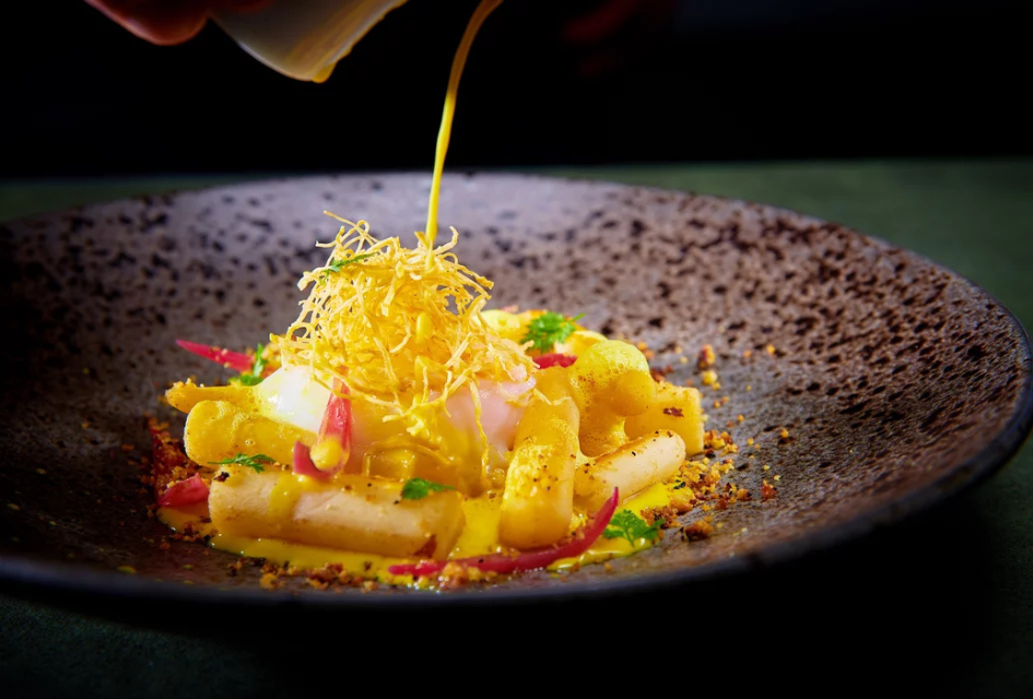 A dish at Le Bistrot with a sauce being poured over atop a crispy nest.
