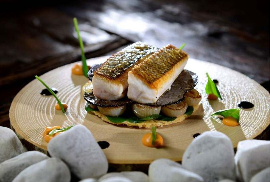 Fish dish at the only Michelin Star restaurants in Verbier, La Table d'Adrien, with decorative garnishes and roasted onions.