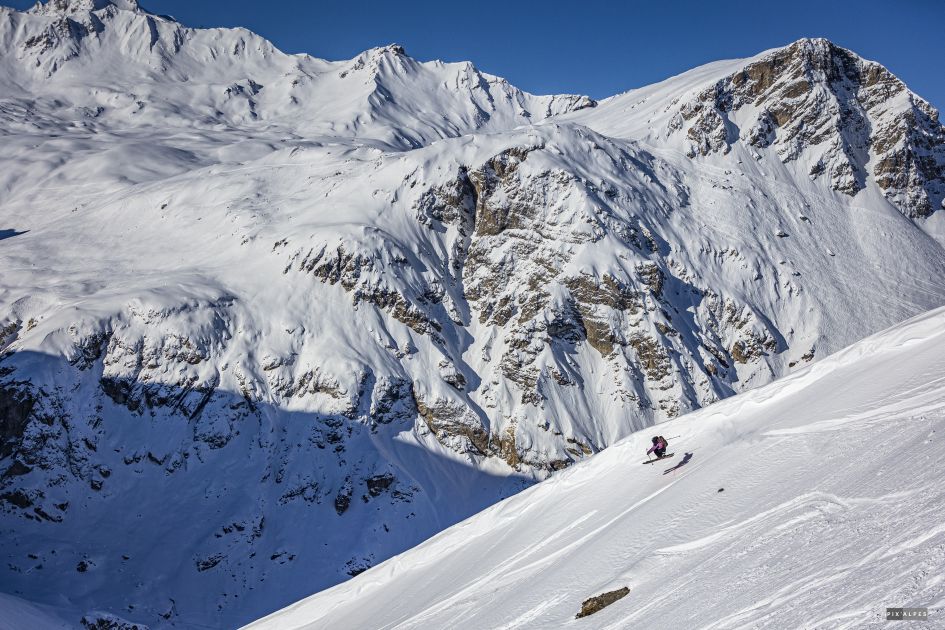 A skier off piste in fresh powder with mountains in the background.