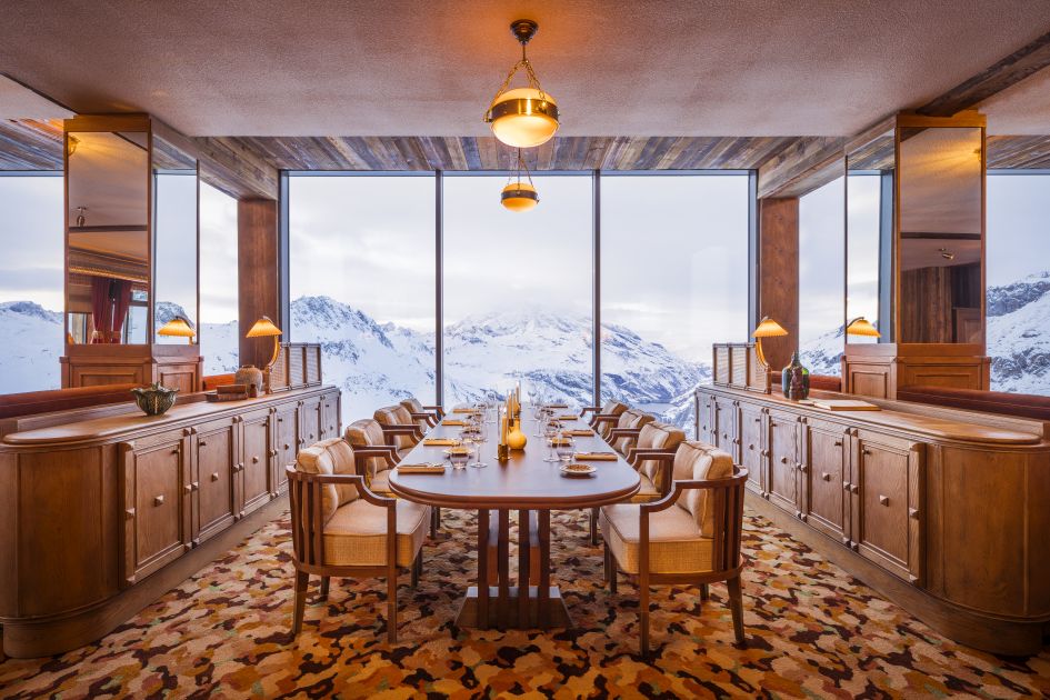 The classy dining room of Le Refuge restaurant in Val d'Isère, with gorgeous mountain views out the windows behind. One of the finest places for a mountain lunch when on your Val d'Isère luxury ski chalet holidays. 