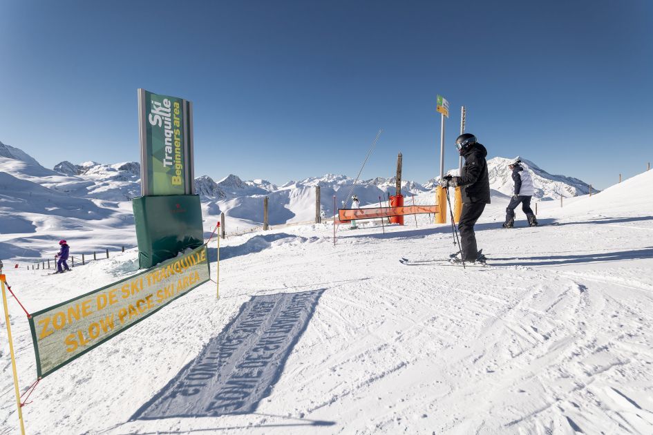 Skiing at the Solaise beginner's area in Val d'Isère, with a slow pace zome and clear blue skies. 