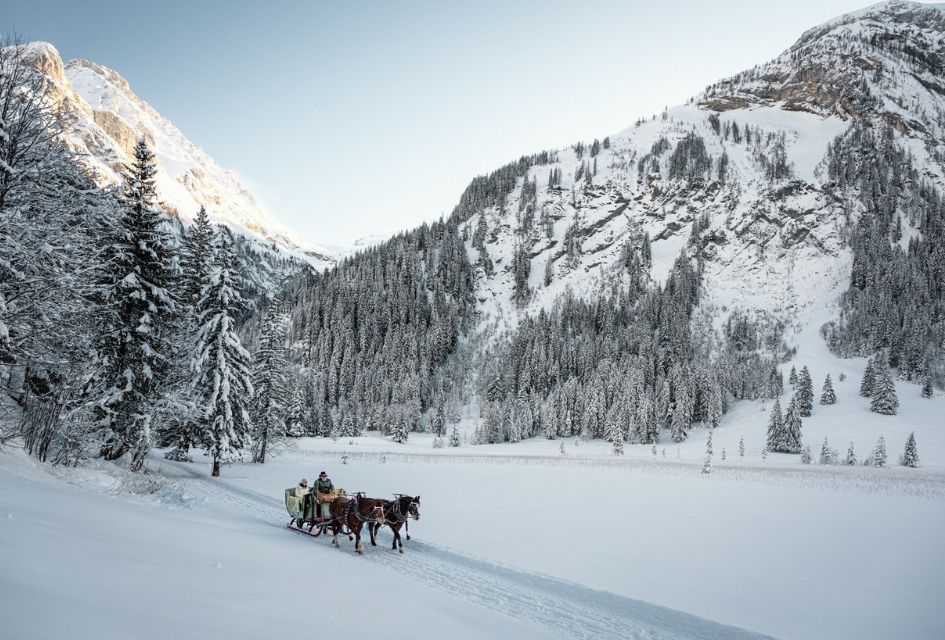 Horse and sleigh being pulled through the snow with mountians in the background in Gstaad, one of the best resorts for Christmas ski holidays.