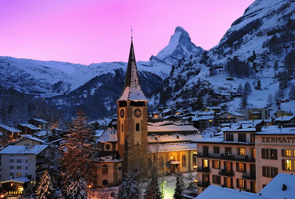 Pink skies behind the Matterhorn, Zermatt and its church festive lights in the town.