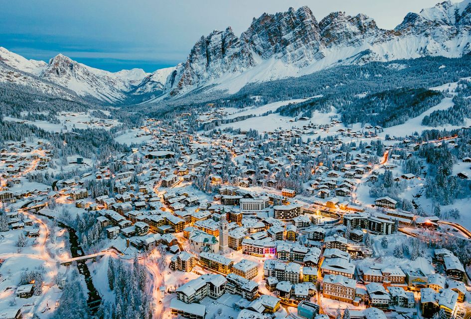 The whole town of Cortina with iconic Italian mountains behind, lit up for the festive season so that visitors can best enjoy this incredible ski resort at Christmas
