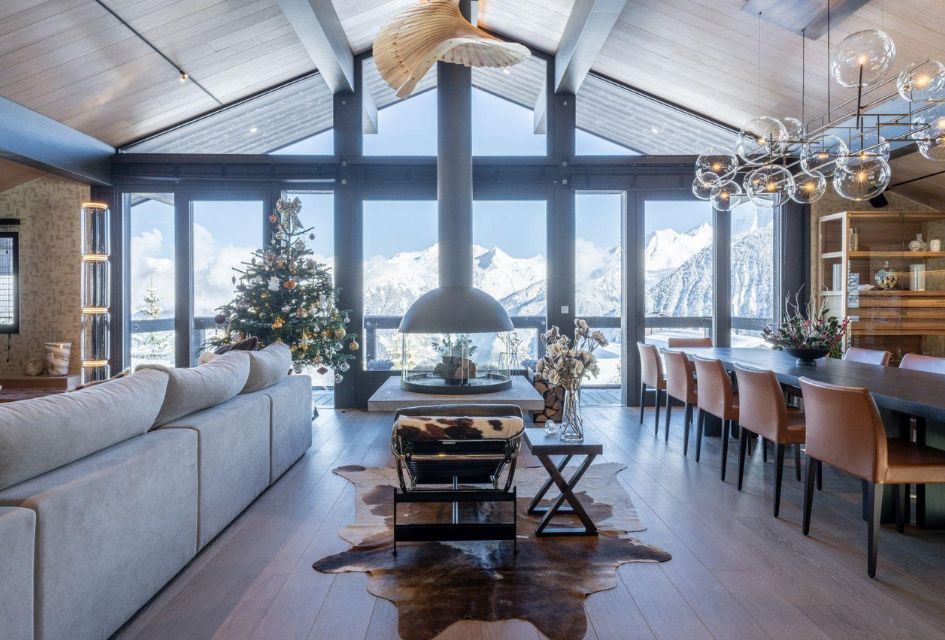 Living room of Chalet B, with a floating central fireplace, dressed Christmas tree, and stunning views and unique furnishings, all in the open-plan space to invite guests for cosy evenings. One of the finest ski-in, ski-out chalets in Courchevel 1850.