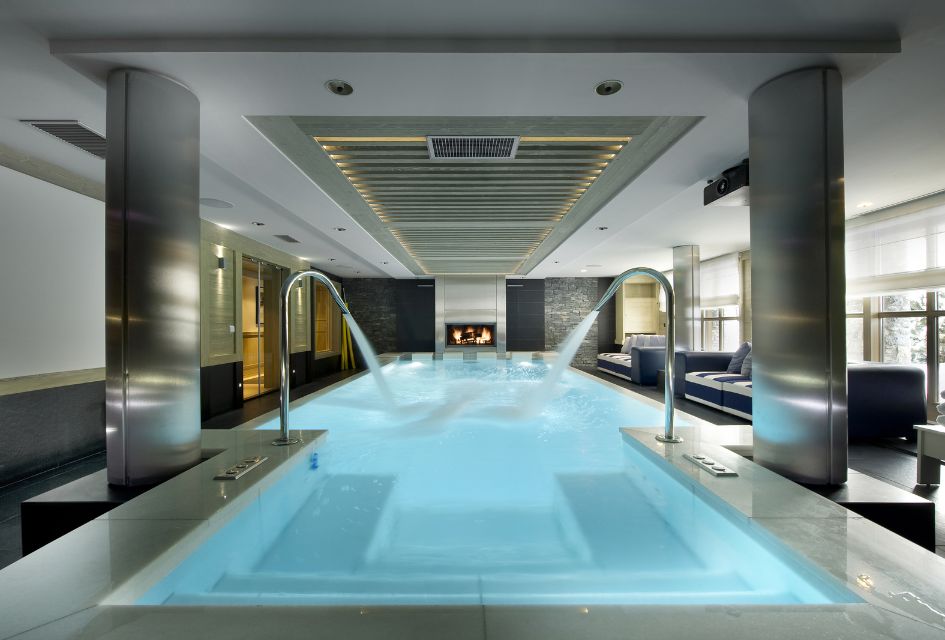 The swimming pool (with jets and a fireplace) of Chalet Hidden Peak, a ski-in ski-out property in Courchevel 1850 that is a part of the incredible Le K2 collection.