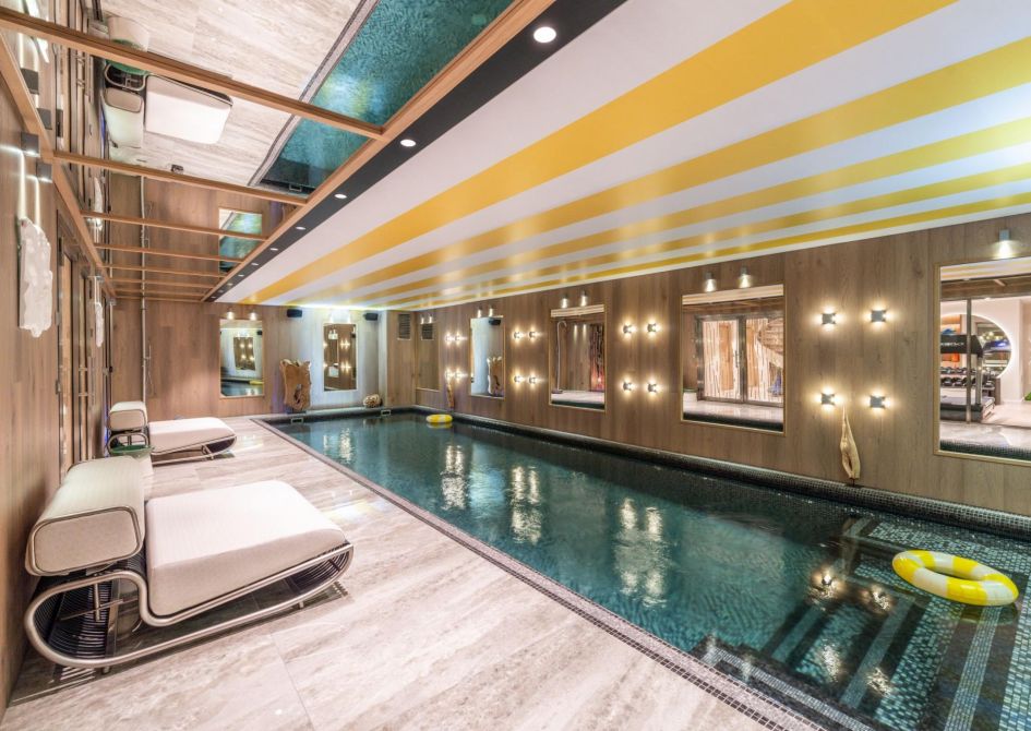 Chalet B in Courchevel 1850 is not only one of the best luxury ski-in, ski-out chalets in France because of its location. Here, we can see a contemporary, vibrant swimming pool space, decorated in light wooden cladding and splashes of yellow.