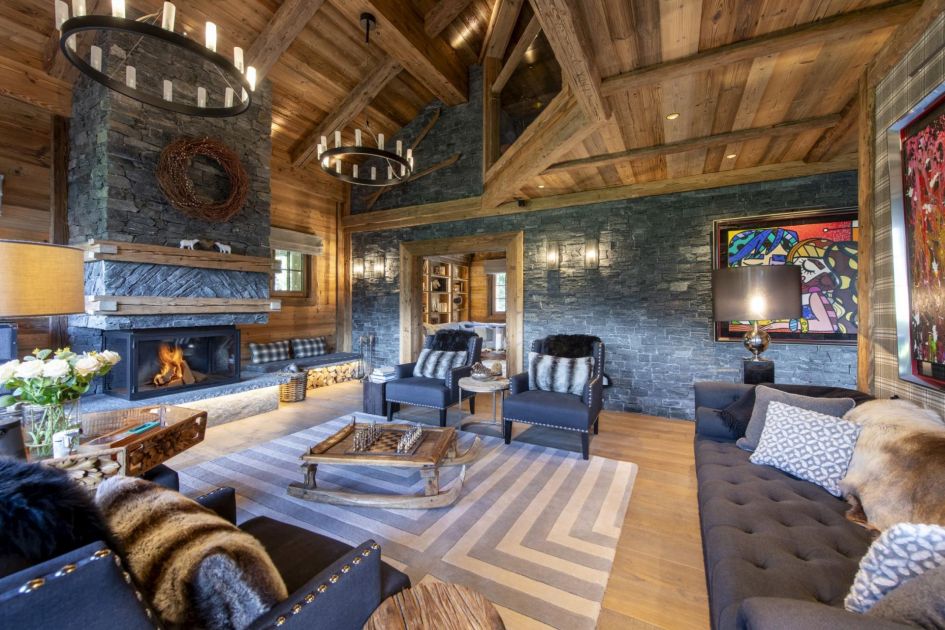Chalet La Tanière's interiors are decorated in a sophisticated alpine-luxe style. In the living area, high wooden ceilings, stone fireplaces and a collection of comfortable sofas and armchairs feature to portray a typical mountain feel!