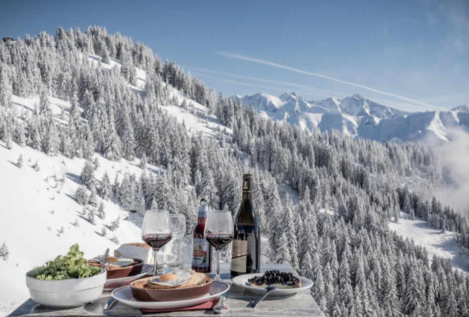 Lunch with red wine overlooking snowy trees and mountains in Megève.