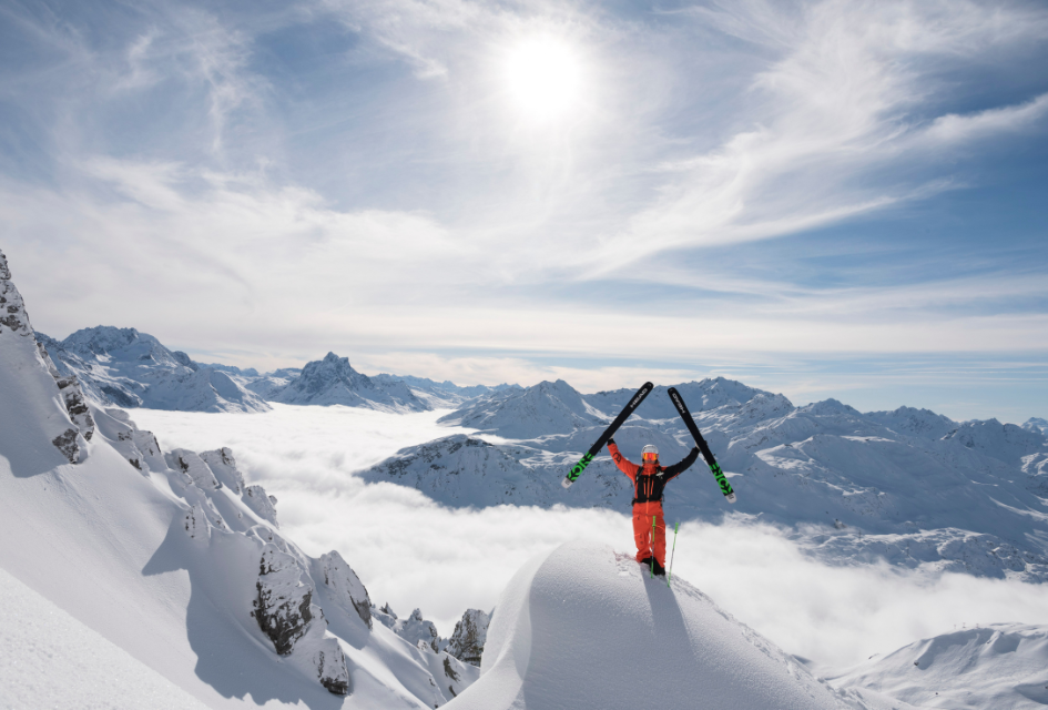 Man holding skis atop mountains of St Anton.