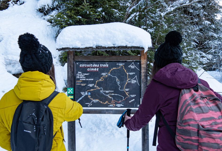 Circuit des Trois Cimes sign in Morzine with two women looking at it, planning their multi resort trip route.